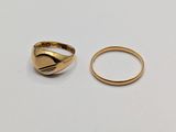 two gold rings sitting on top of each other on a white surface