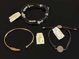 three bracelets and a coin are on a black surface