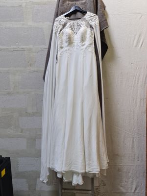 a white dress hanging on a clothes rack next to a brick wall