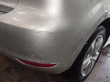 the rear end of a silver car with a denting dent on it