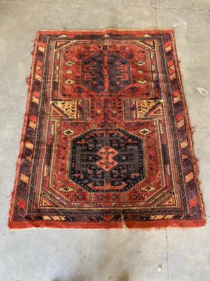 a red and black rug sitting on top of a cement floor