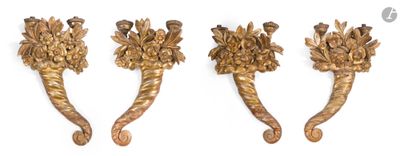 trois crochets métalliques dorés ornés de fleurs, posés sur une surface blanche