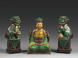 trois figurines vertes et dorées d'un homme et d'une femme assis sur un banc