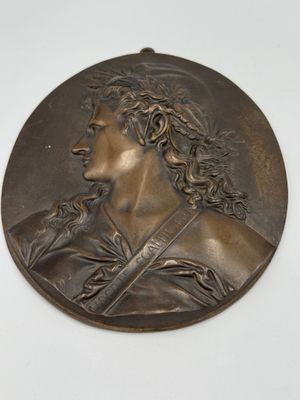 bronze medallion of a man with long hair and a beard