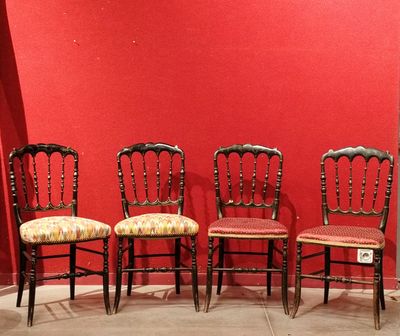 four antique chairs are lined up against a red wall