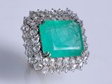 an image of a ring with a green stone surrounded by clear crystals