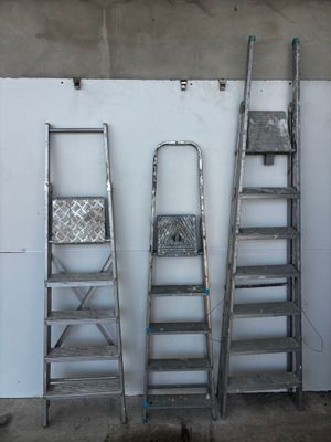 several ladders are lined up against a white wall in a room