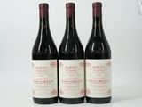 trois bouteilles de vin rouge posées l'une à côté de l'autre sur une surface blanche