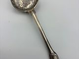 an antique silver spoon with a handle on a white surface