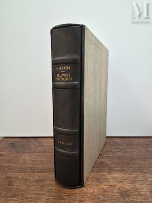 un vieux livre posé sur une table en bois à côté d'un mur blanc