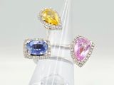three different colored gems are set in a ring on a clear ring holder