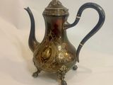an antique silver tea pot with a blue handle sitting on a white surface