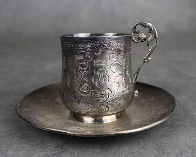 une tasse et une soucoupe en argent posées sur une soucoupe