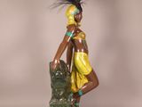 statue of a woman in a yellow dress sitting on a green chair
