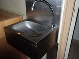 un lavabo en acier inoxydable dans une salle de bains, sur lequel est posé un micro-ondes