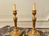 a pair of brass candlesticks on a marble table