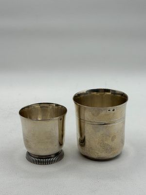 pair of silverplated cups with beaded rims on a white surface