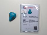 une pierre bleu turquoise en forme de cœur posée à côté d'une carte sur une surface blanche