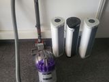 un aspirateur posé par terre à côté de quelques rouleaux de papier toilette