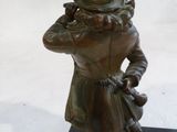 statue en bronze représentant un homme portant un haut-de-forme et un manteau, tenant un pistolet