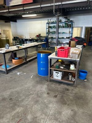 a large room with a lot of work tables and blue barrels