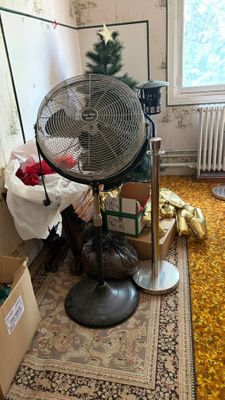 un ventilateur dans un coin de la pièce, à côté d'un sapin de Noël
