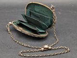 a green purse with a chain around it on a table