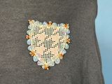 grey sweater with a heart shaped brooch on the chest