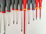 seven different types of screwdrivers lined up on a white surface