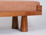 an upholstered bench with two wooden legs and a pink upholstered seat