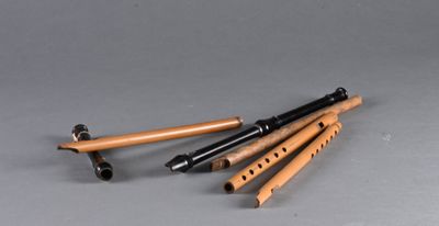 four wooden flutes are lined up on a gray surface