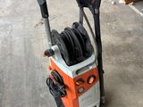 une machine à pression électrique orange et noire posée sur un sol en béton