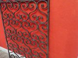 a close up of a metal screen with a red wall in the background