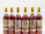 six bouteilles de vin sont alignées sur une surface blanche