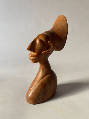 une image représentant une sculpture en bois d'une femme portant un chapeau sur la tête