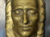 a gold sculpture of a man ' s face on a metal surface