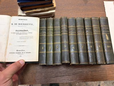 une personne tenant une pile de vieux livres posée sur une table
