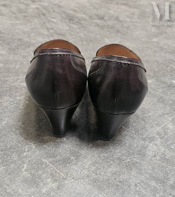 une paire de chaussures en cuir noir posée sur un sol gris