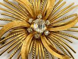 an image of a gold flower brooch with a crystal center