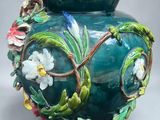 a green vase with flowers and vines painted on it