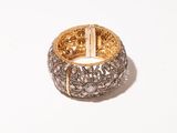 a close up of a gold and diamond bracelet on a white surface