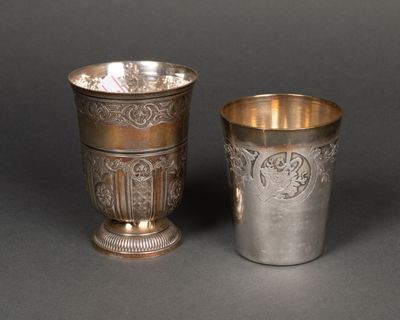 une paire de tasses en argent ornées de motifs, posées sur une table