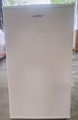 une photo d'un petit réfrigérateur blanc dans un salon
