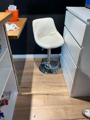 une chaise blanche placée devant un bureau sur lequel se trouve un ordinateur