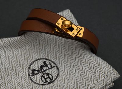 a brown leather bracelet with a gold buckle on it