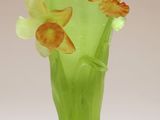 un vase vert contenant des fleurs, posé sur une surface blanche