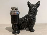 a small black dog statue next to a lighter
