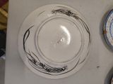 a white plate with a design on it next to a plate with a design on it