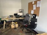 a room with a desk, chairs, and a computer on it