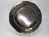 a silver plate on a metal stand on a white surface